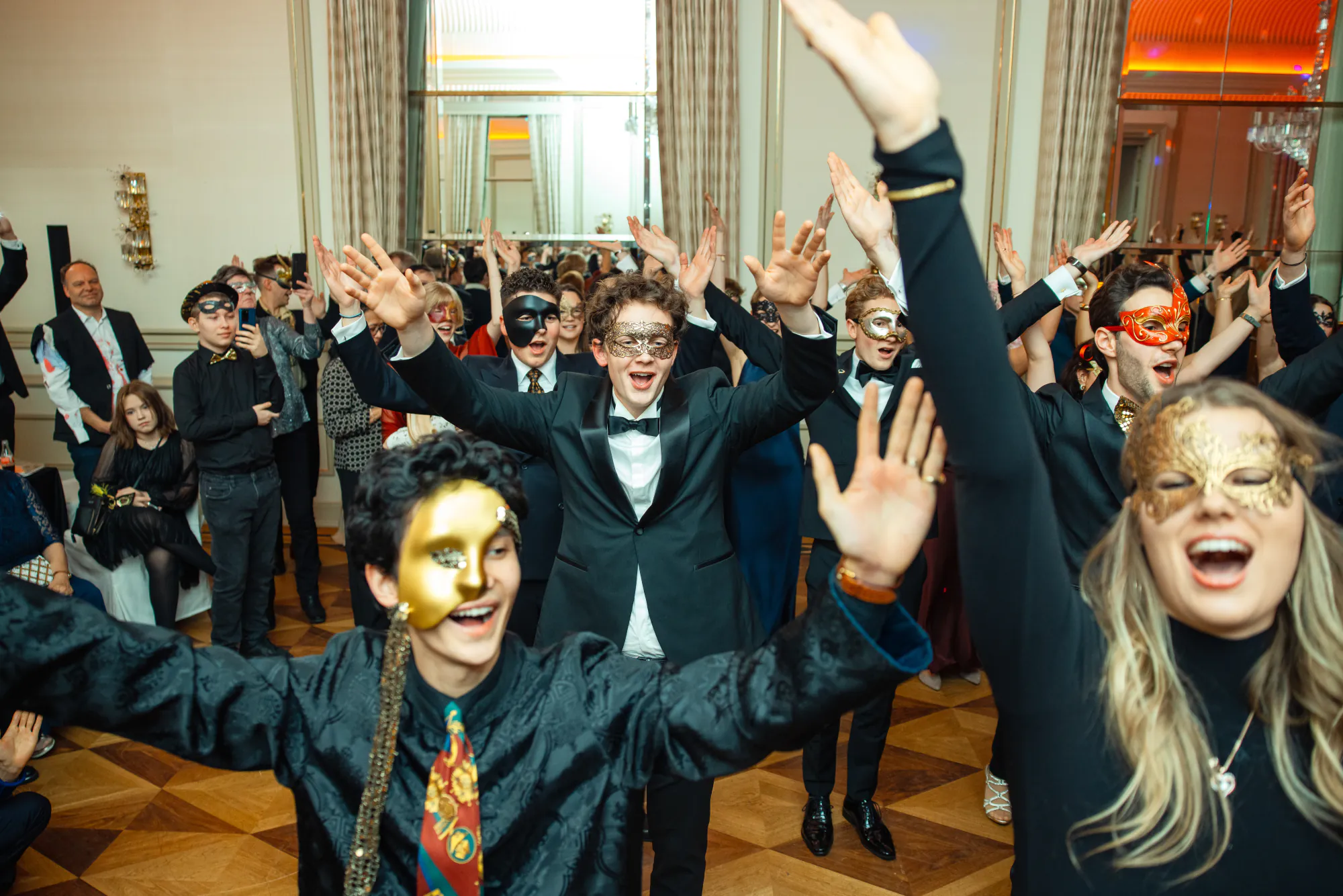 Gäste in Masken tanzen mit erhobenen Armen, Stimmung bei der Weihnachtsfeier in Hamburg